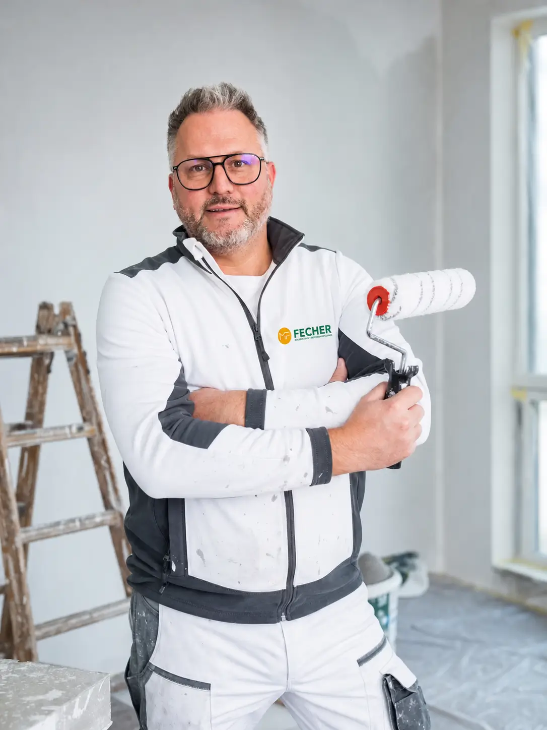 Markus Fecher, Maler- und Lackierermeister, in Arbeitskleidung mit Farbrolle in einem Raum während der Renovierung